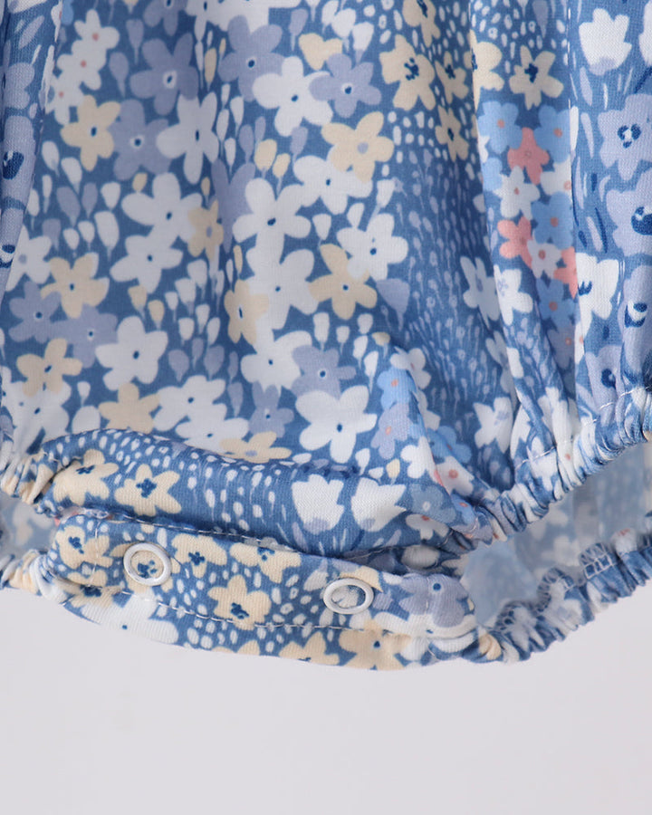 Blue floral bubble romper with elastic leg cuffs and gathered ruffle hem detail