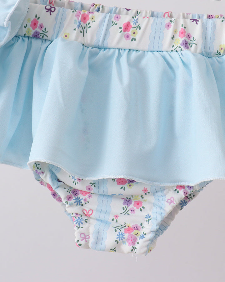 Light blue swim bottoms with floral waistband and bottom trim on a white background