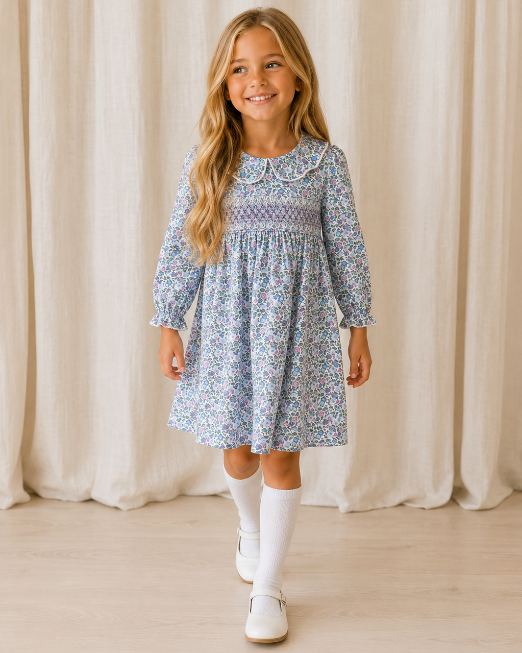 Blue floral smocked dress with long sleeves and Peter Pan collar, worn with white shoes