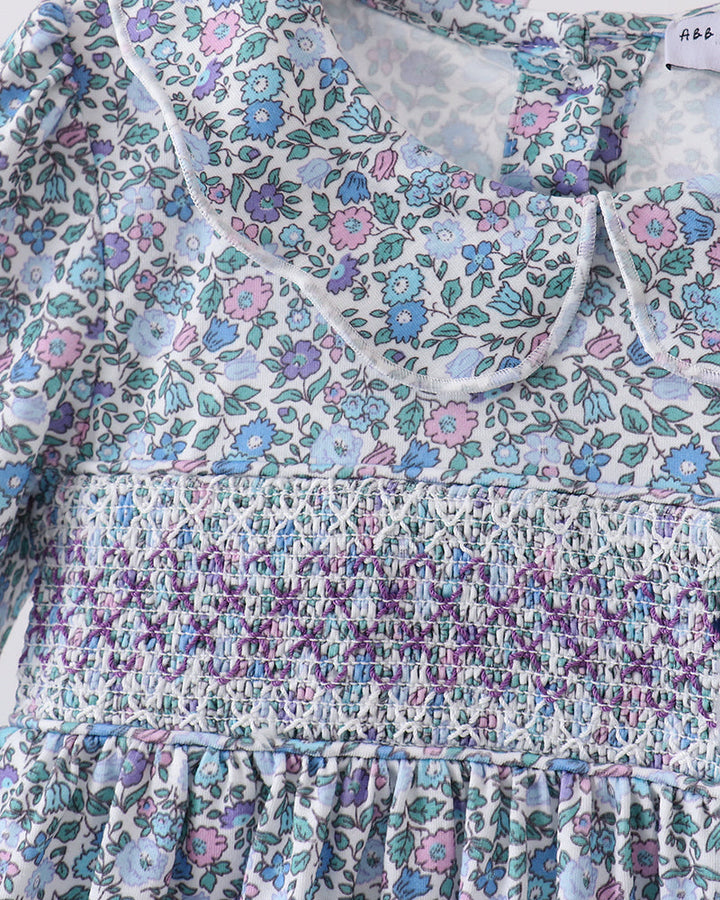 Floral smocked yoke dress detail, rounded neckline and long sleeves, light blue ground