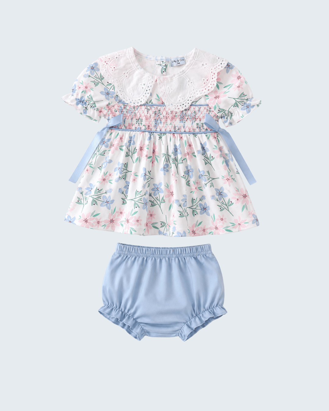 Baby girl's floral top and blue bloomers set on a light gray background