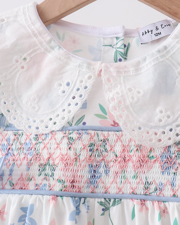Floral dress with smocked details on a hanger, featuring the brand &