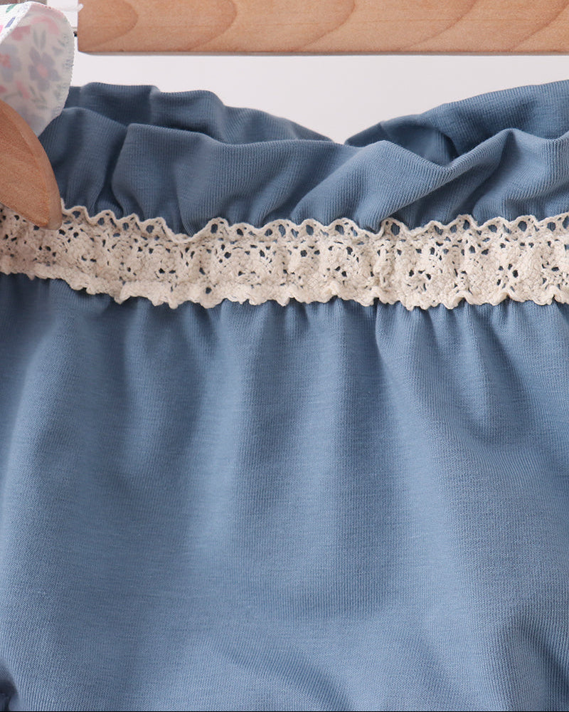 Blue fabric with lace trim on a wooden hanger against a white background