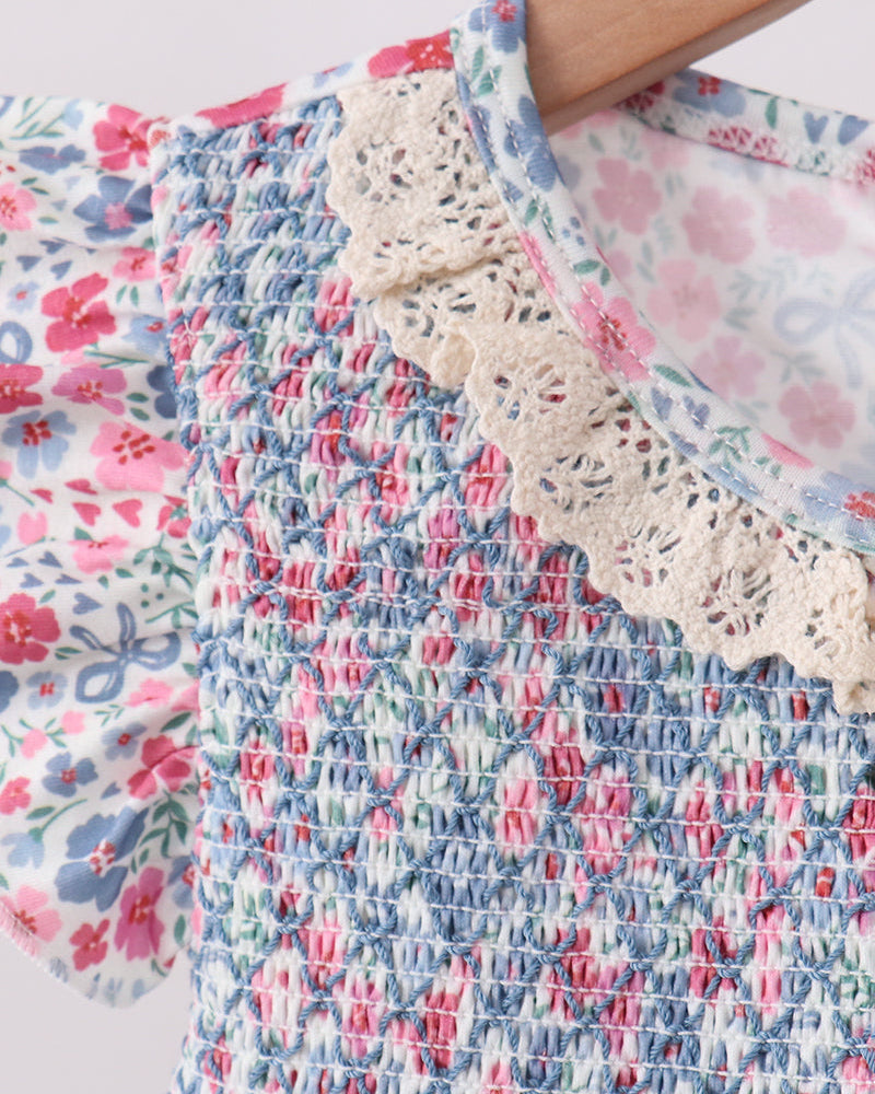 Close-up of a floral dress with lace trim on a light background
