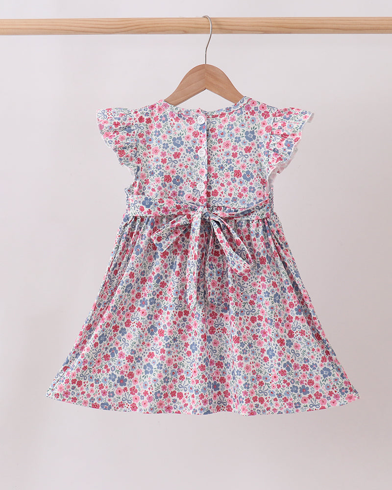 Floral dress hanging on a wooden hanger against a plain background