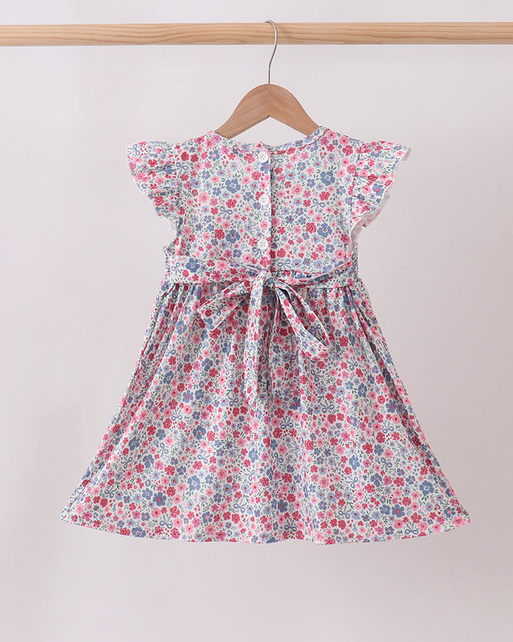 Floral dress hanging on a wooden hanger against a plain background