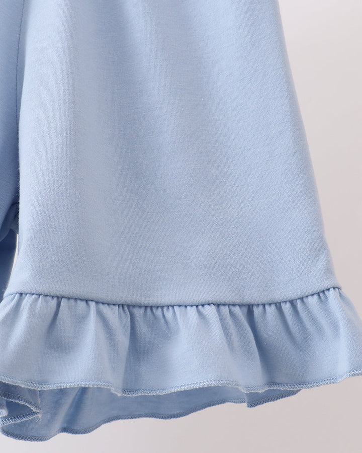 Light blue shorts with ruffled hem on a neutral background