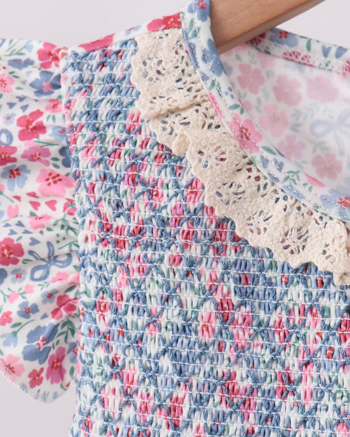 Close-up of a floral dress with lace trim on a light background