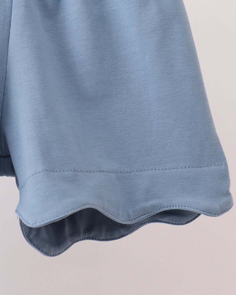 Close-up of a blue garment with a scalloped edge on a light gray background