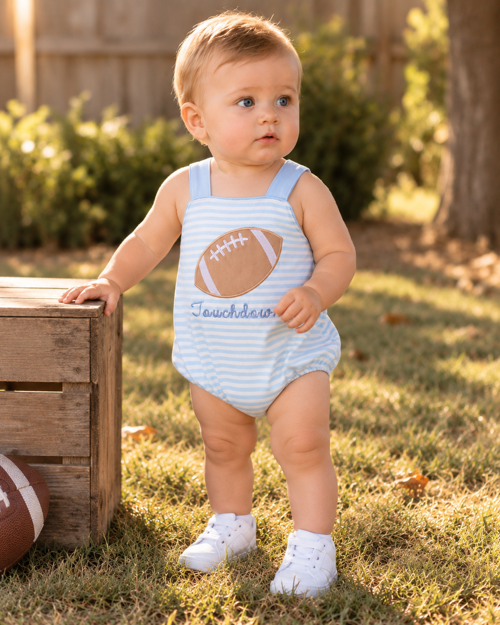 Blue and white striped baby romper with football applique and “Touchdown” embroidery, front view