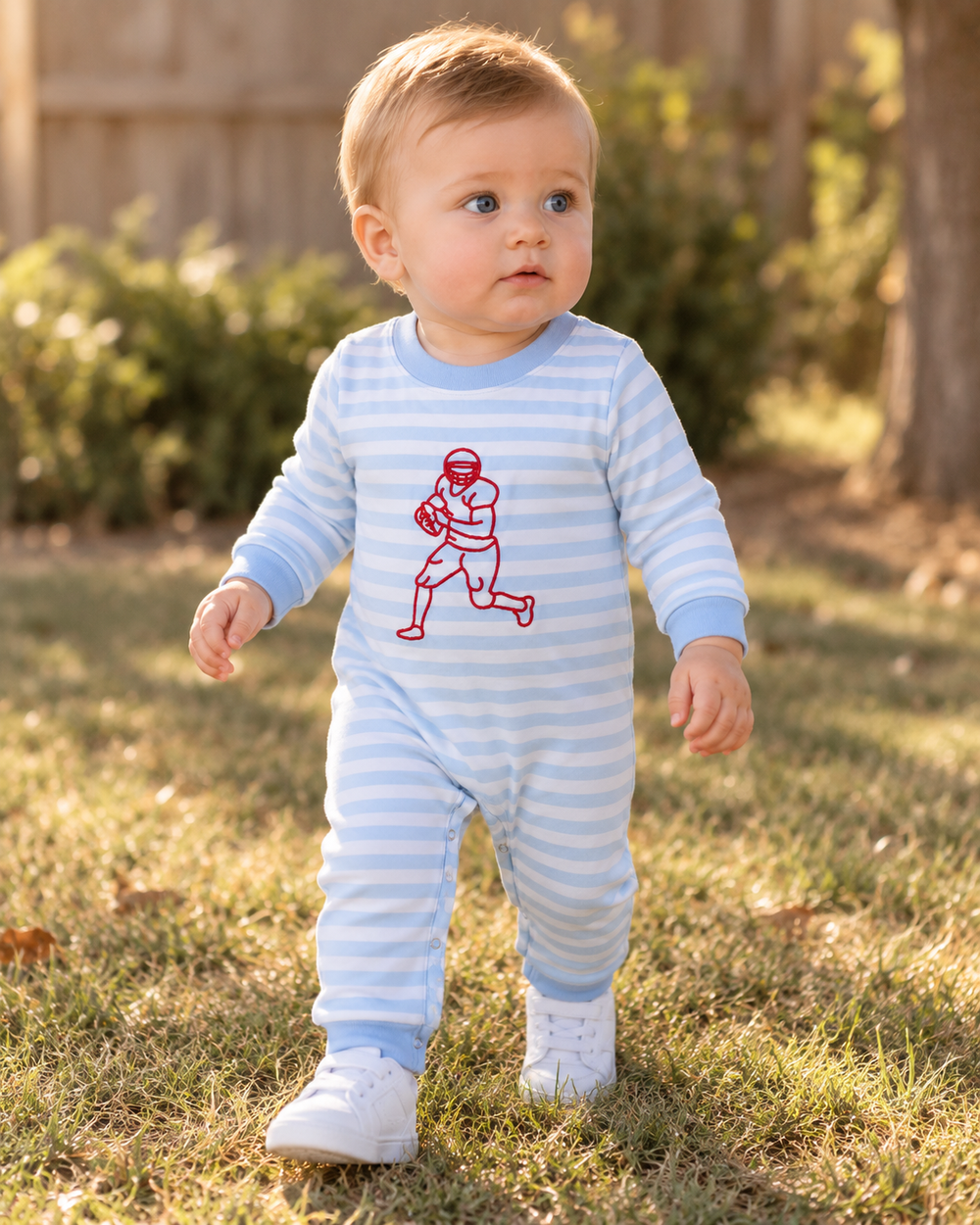 Light blue striped footed romper with red football player embroidery on baby