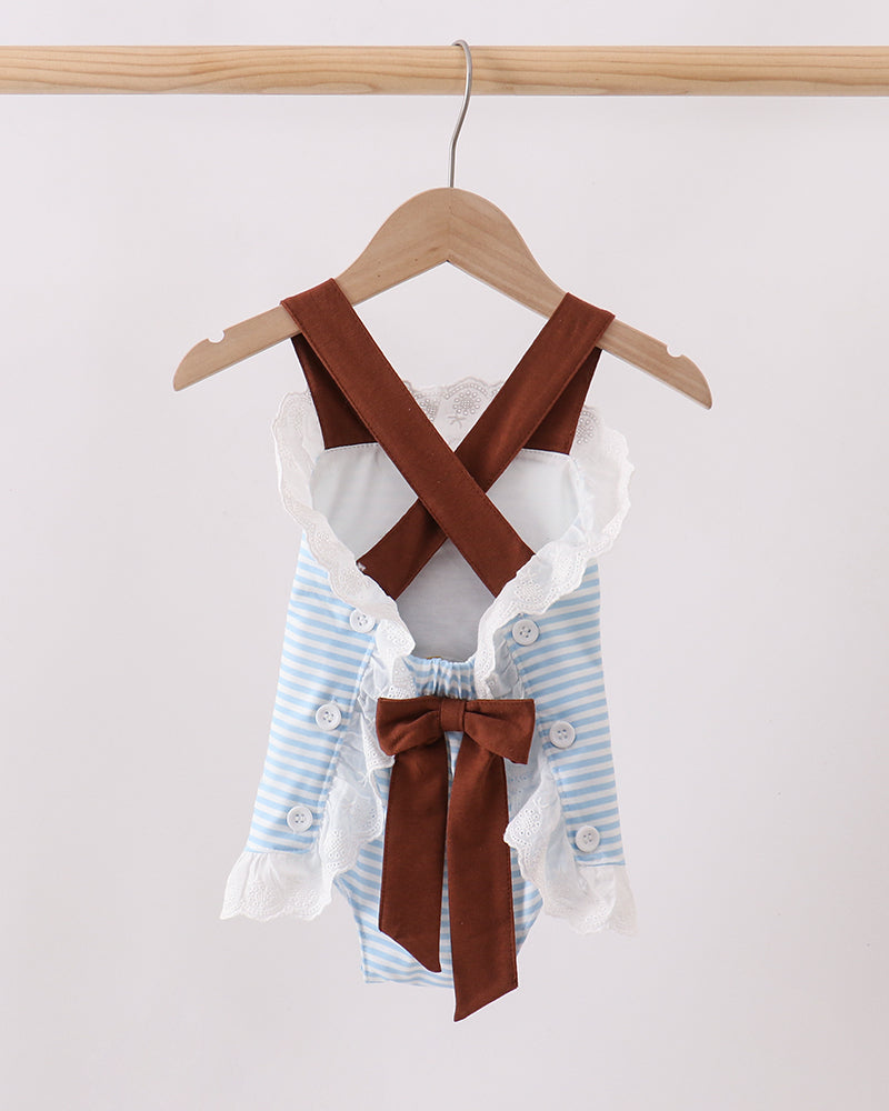 A baby romper with light blue and white stripes, white ruffle trim, and brown suspenders, hanging on a wooden hanger against a plain light background.