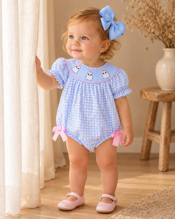 Blue gingham ghost romper on a toddler with pink bows and flutter sleeves.