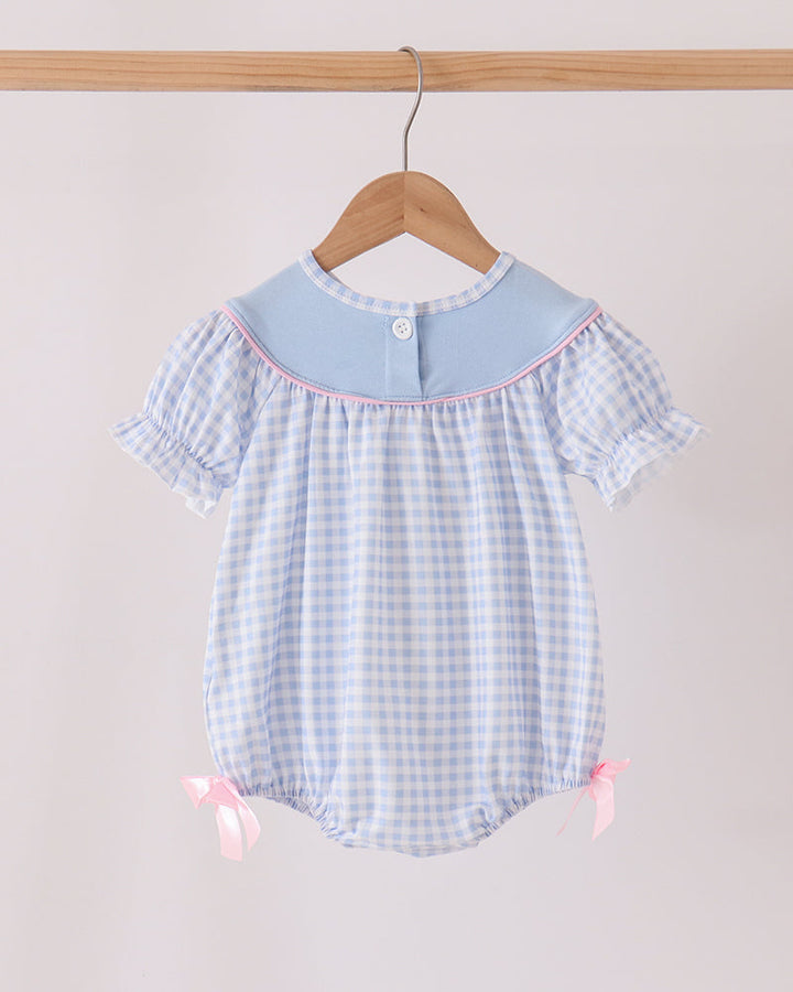 Blue gingham bubble romper with short flutter sleeves and pink side bows at legs.
