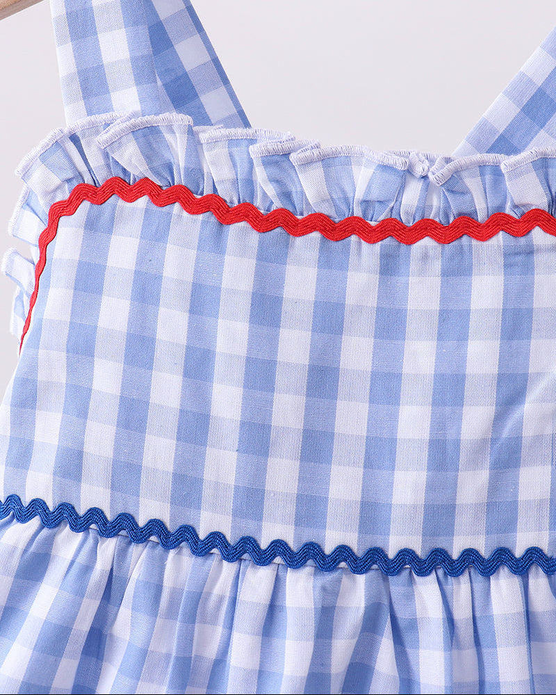 Blue and white checkered dress with red trim on a wooden hanger.