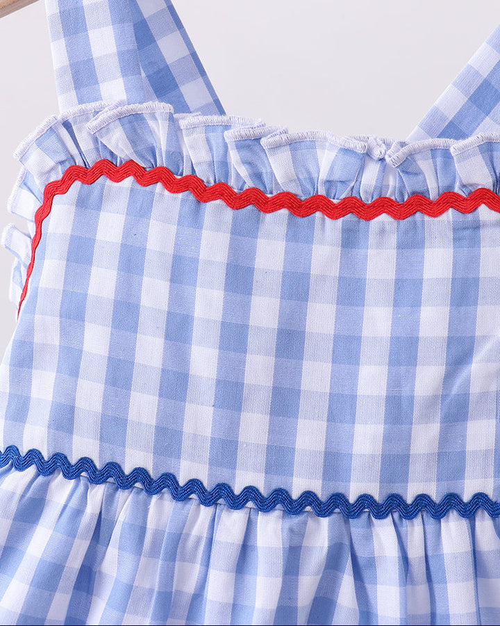 Blue and white checkered dress with red trim on a wooden hanger.