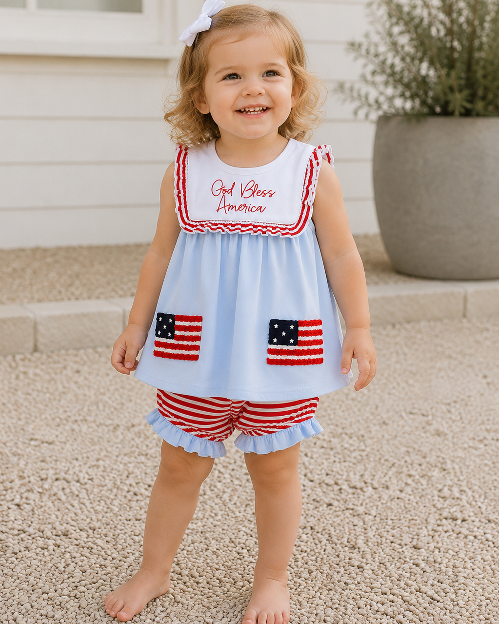 Young girl standing outside wearing Blue God Bless America Flag French Knot Ruffle Bloomer Set