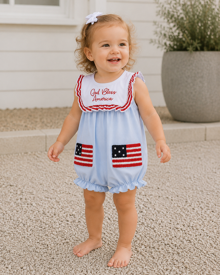 Child wearing a light blue romper with American flag designs and &