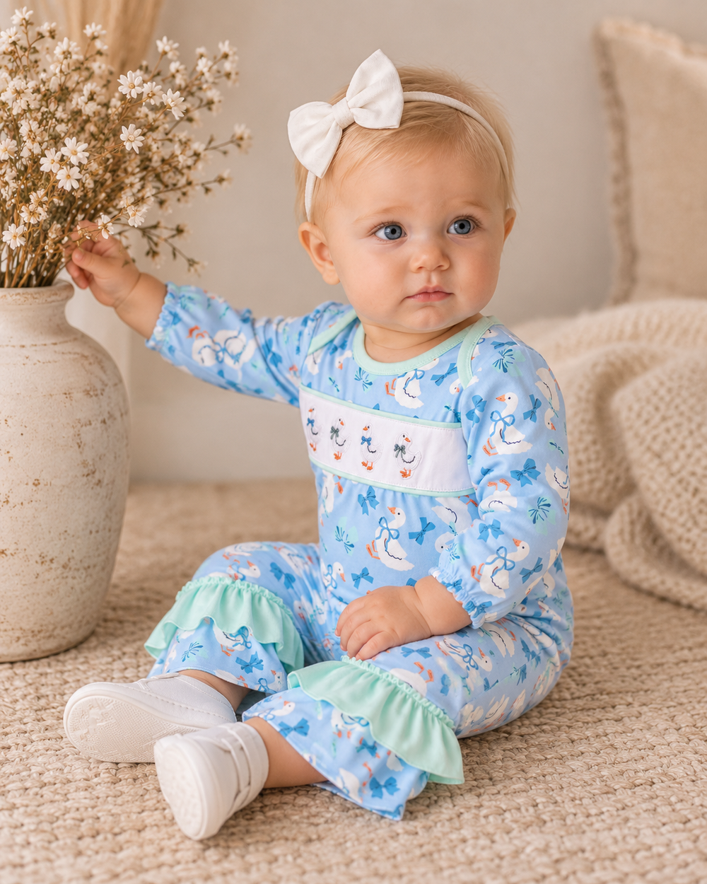 Blue animal-print baby romper with mint ruffle hem, worn by child on couch.