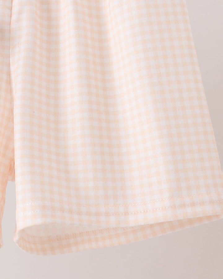 A close-up of a light yellow and white gingham checkered fabric, showing the texture and pattern of the material.