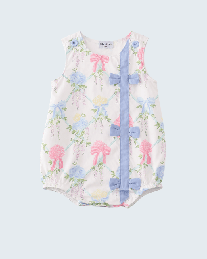 Baby romper with floral and bow pattern on a light gray background