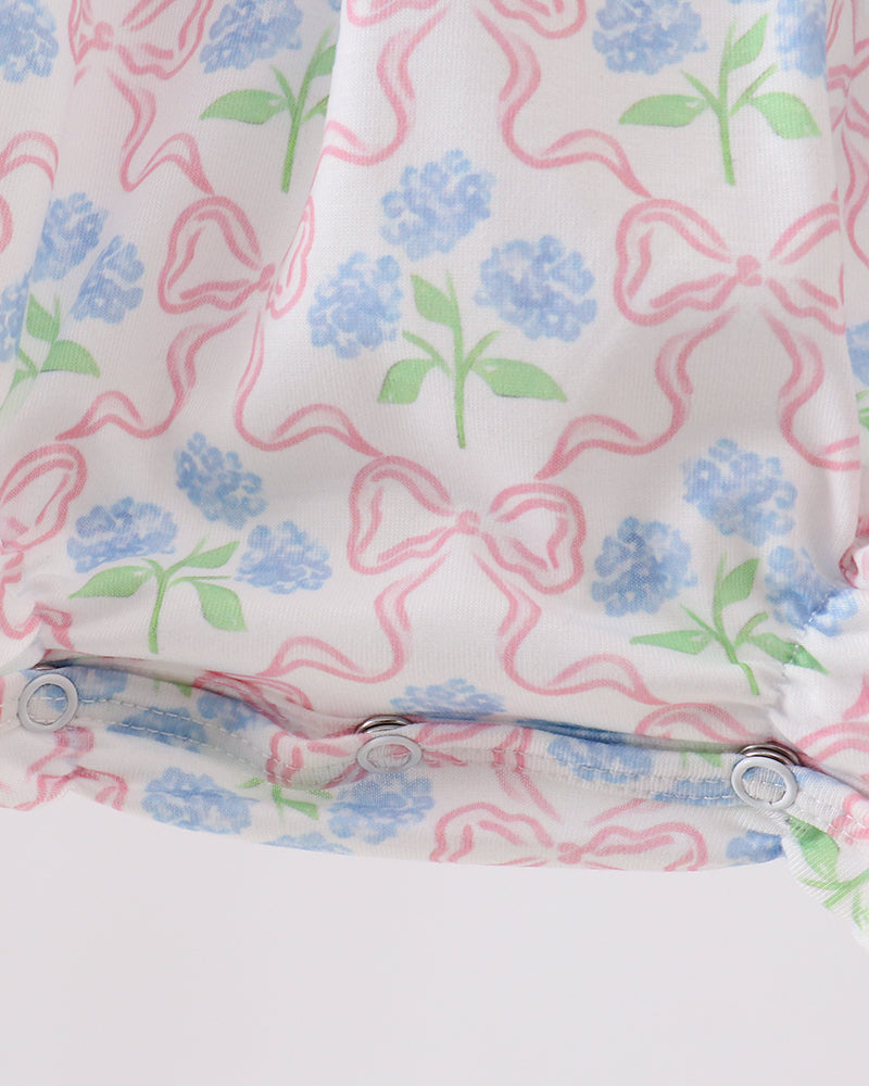 Close-up of a fabric with pink bows and blue flowers on a white background
