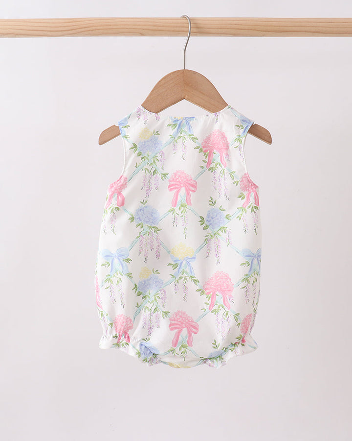 Baby romper with floral pattern on a wooden hanger against a white background