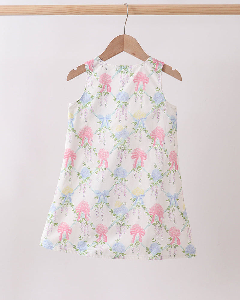 Floral dress with pink and blue flowers on a hanger against a white background