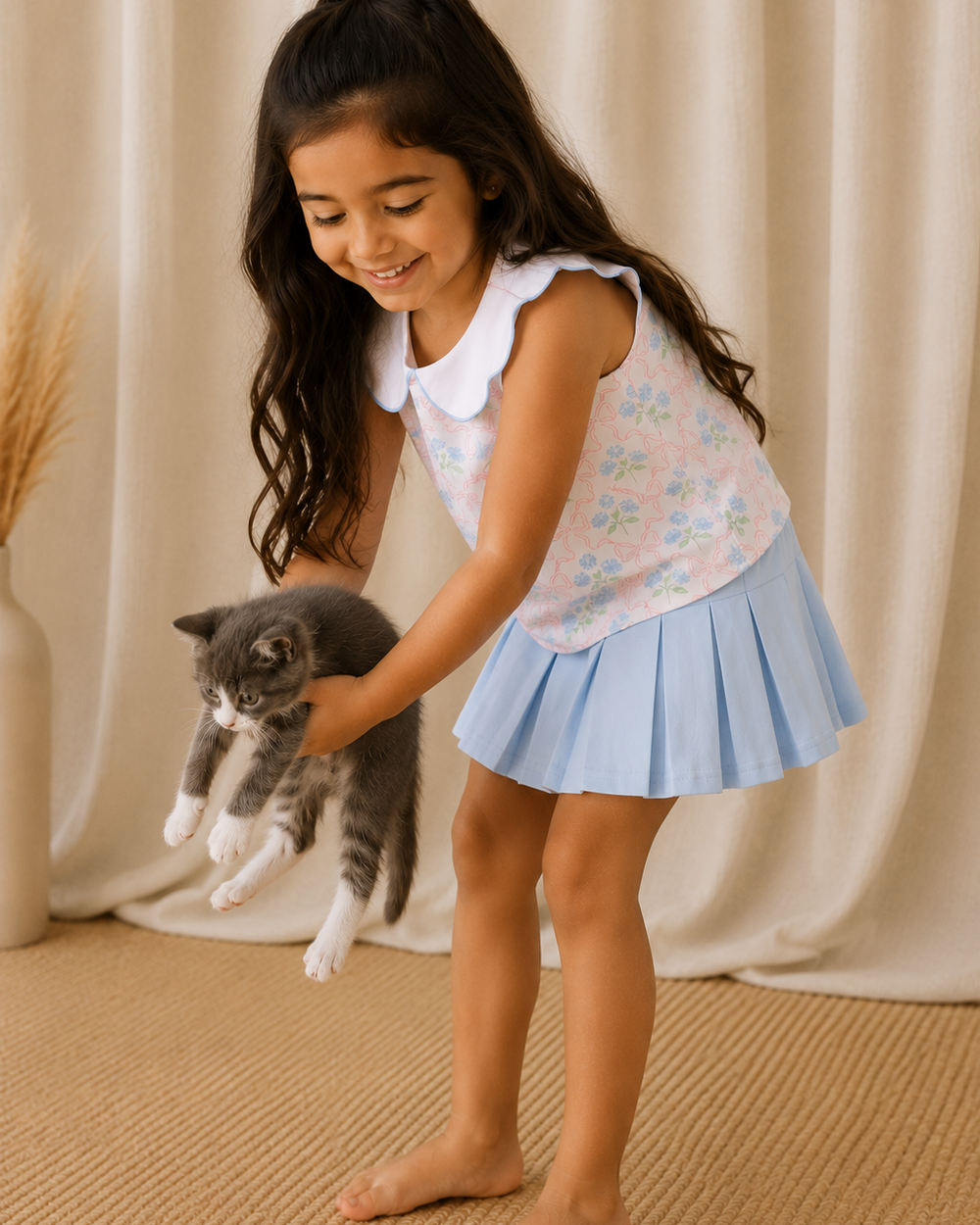 Young girl playing with a cat in front of a beige curtain