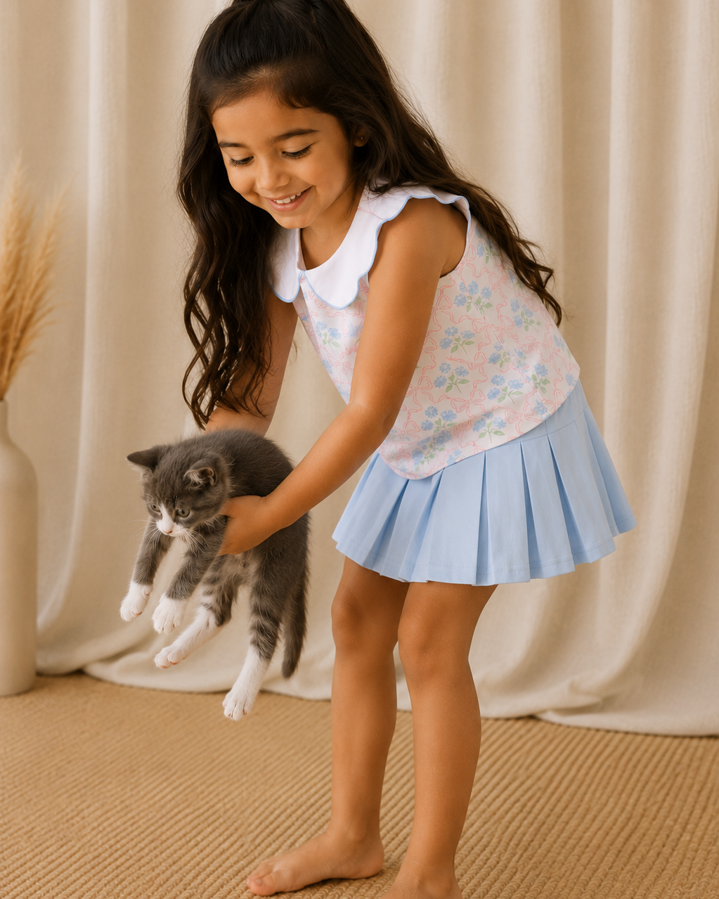Young girl playing with a cat in front of a beige curtain