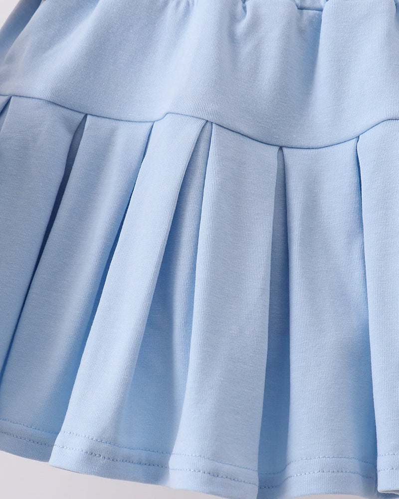 Close-up of a light blue pleated skirt on a neutral background