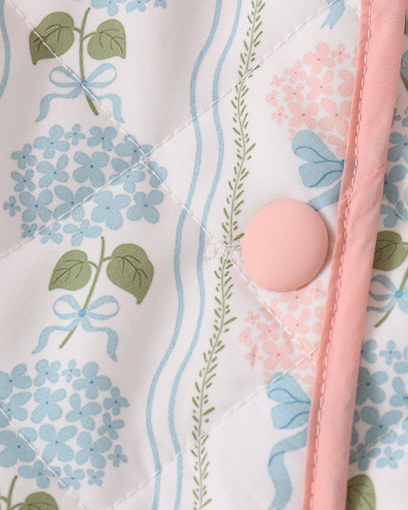 Blue floral jacket close-up with pink trim and round button on placket