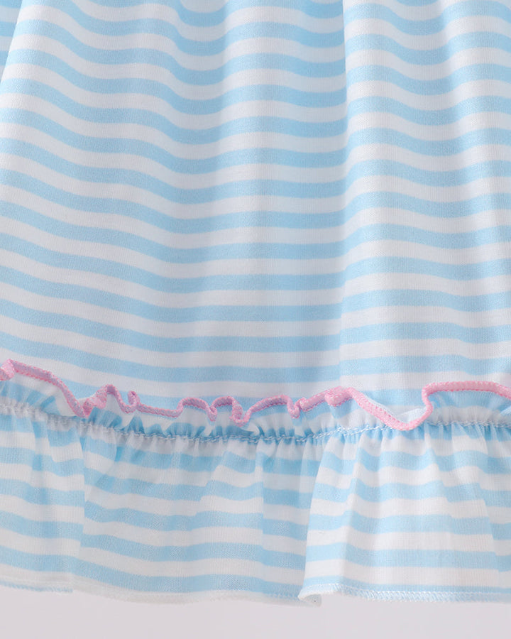 Close-up of a blue and white striped fabric with pink trim on a light gray background