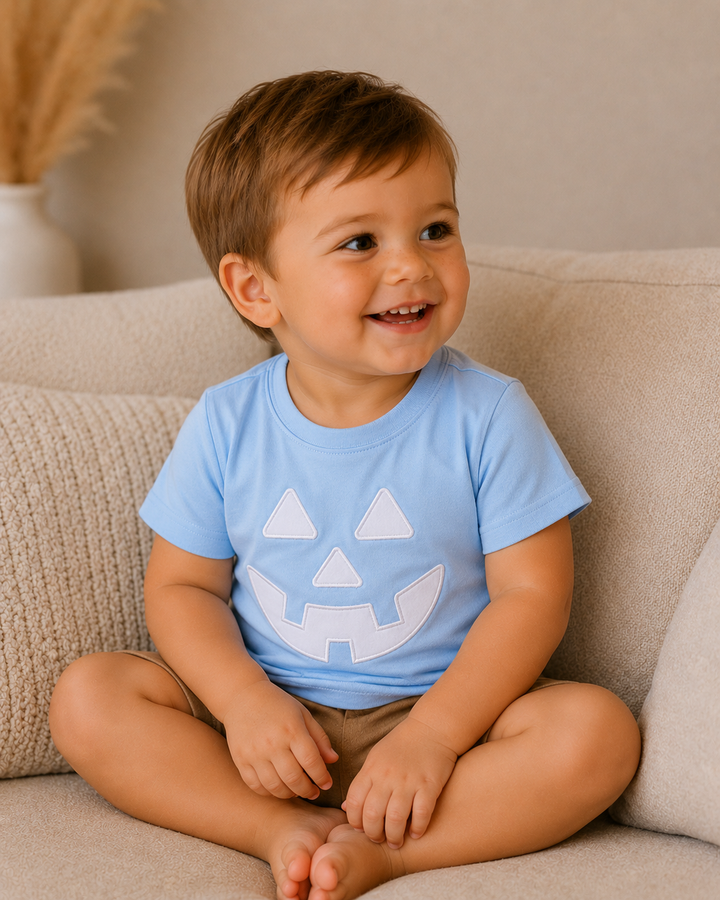 Light blue short-sleeve top worn by baby with white jack-o-lantern face applique