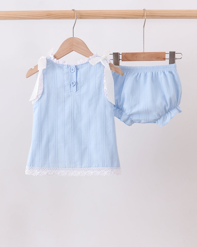 A two-piece baby outfit set consisting of a light blue sleeveless top with white lace trim and matching light blue bloomers, hanging on wooden hangers from a wooden rod against a plain white background.