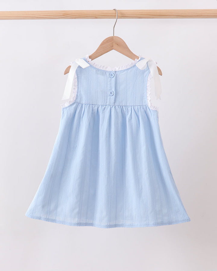 A light blue sleeveless baby dress with white lace shoulder details and a buttoned neckline, hanging on a wooden hanger against a plain white wall.