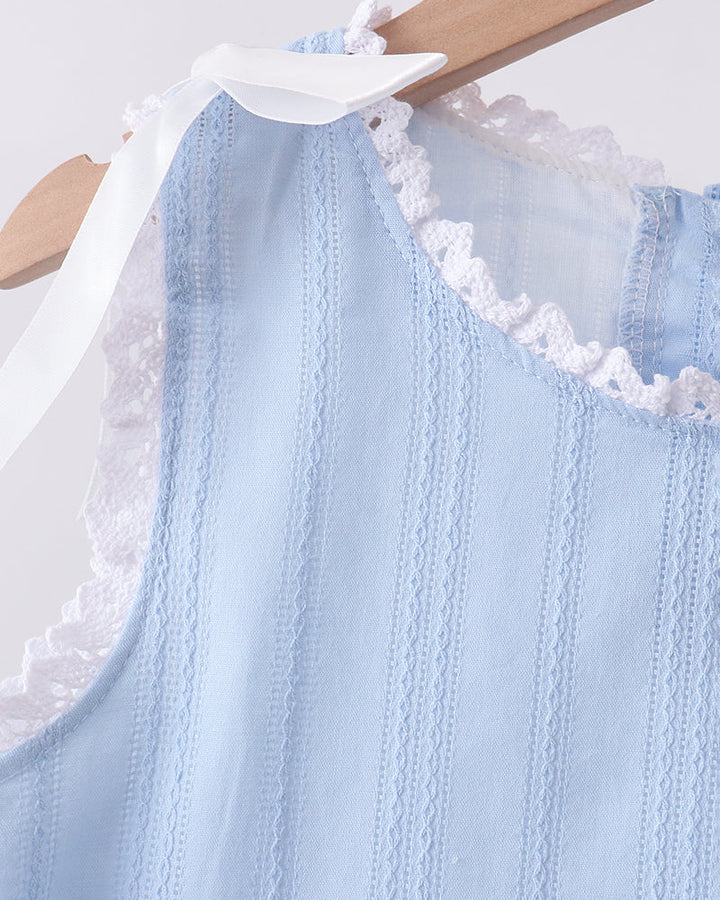 A light blue sleeveless top with vertical textured stripes and white lace trim, hanging on a wooden hanger with a white ribbon bow.