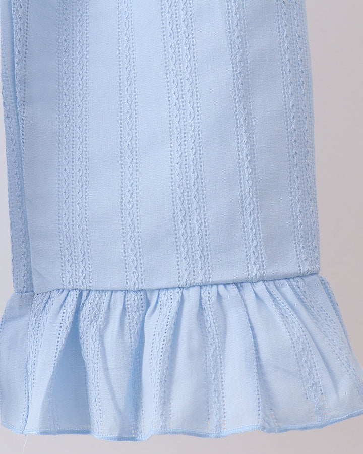 Close-up of a light blue eyelet fabric garment, showing vertical embroidered stripes and a ruffled hem against a plain light background.