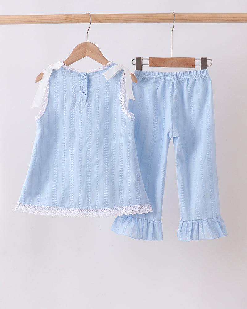 A two-piece baby clothing set hanging on wooden hangers from a light wood rod. The set includes a light blue sleeveless top with white lace trim and a matching pair of light blue pants with ruffled hems.