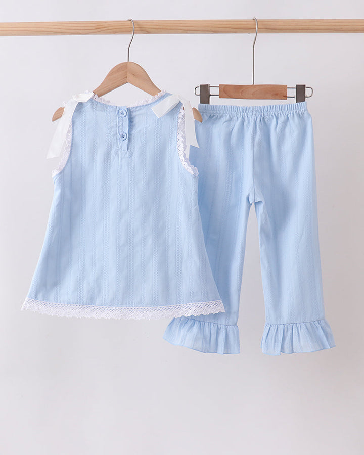 A two-piece baby clothing set hanging on wooden hangers from a light wood rod. The set includes a light blue sleeveless top with white lace trim and a matching pair of light blue pants with ruffled hems.