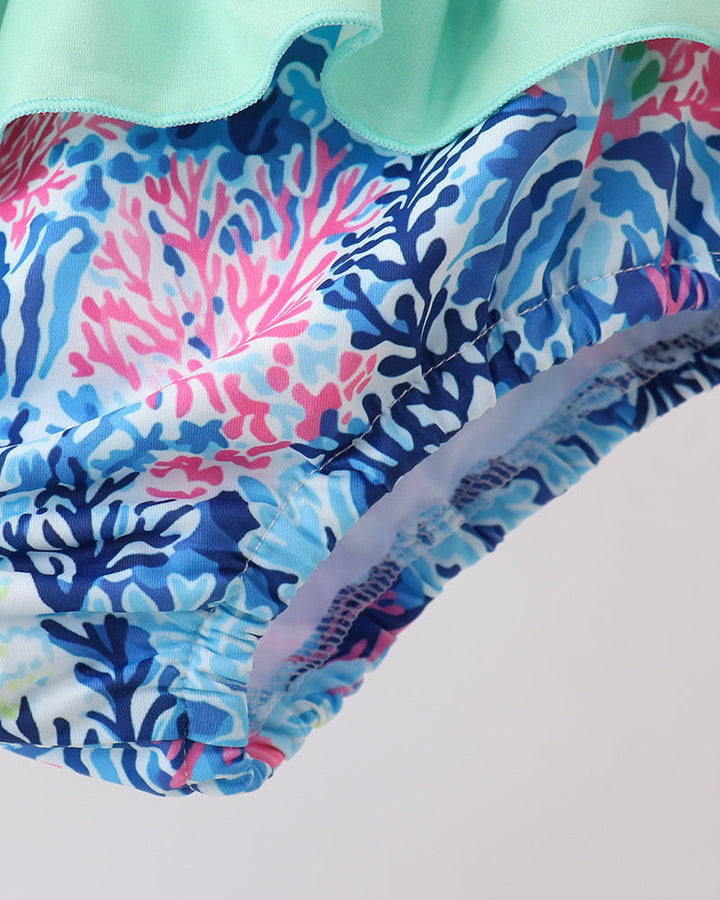 Close-up of a swimsuit with a colorful coral pattern on a light background