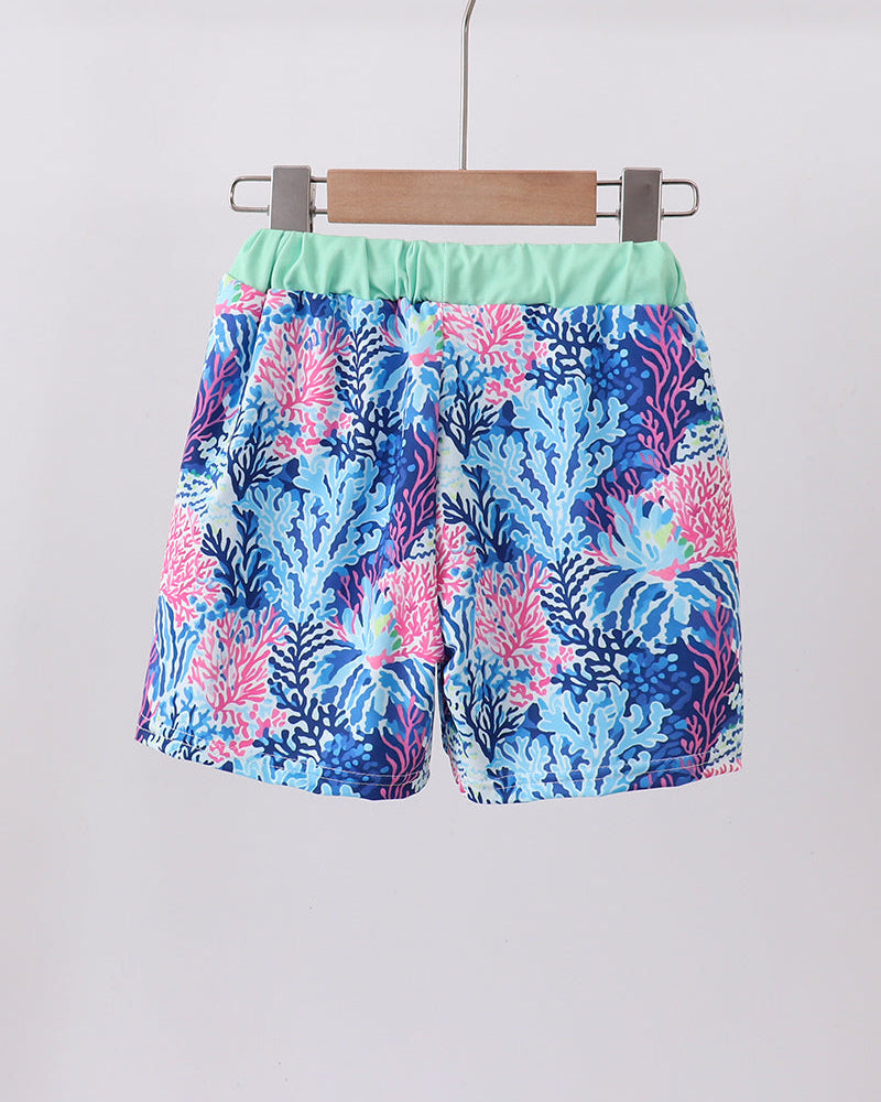 Colorful floral shorts hanging on a wooden hanger against a white background