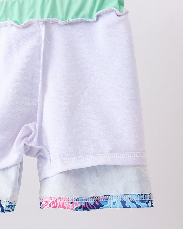 White garment with green and multicolor trim on a white background