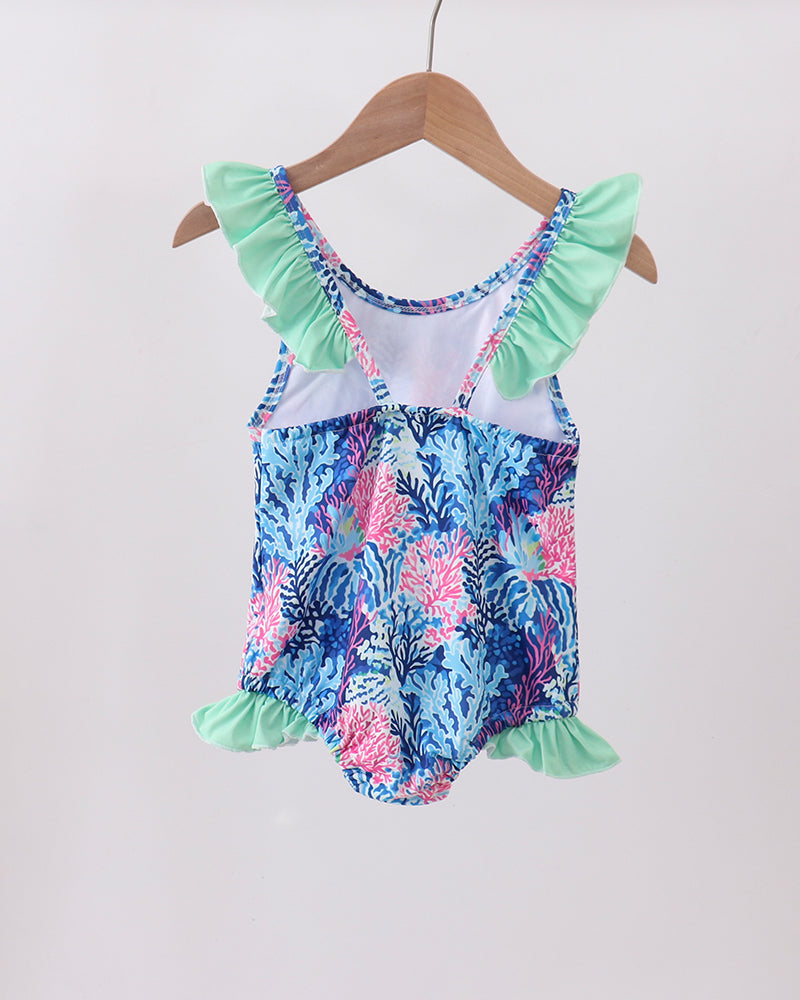 Floral-patterned swimsuit with ruffled details on a wooden hanger against a white background
