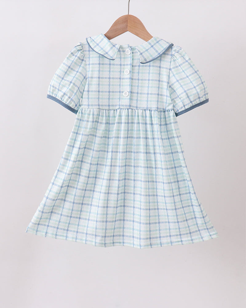 Green and white checkered dress on a hanger against a plain background