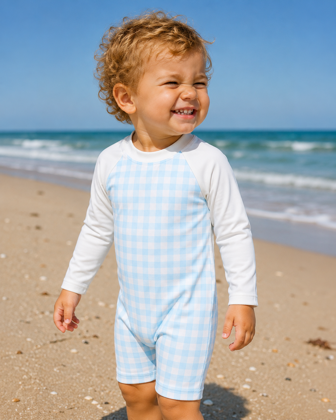 Child wearing a light blue and white checkered outfit on a beach