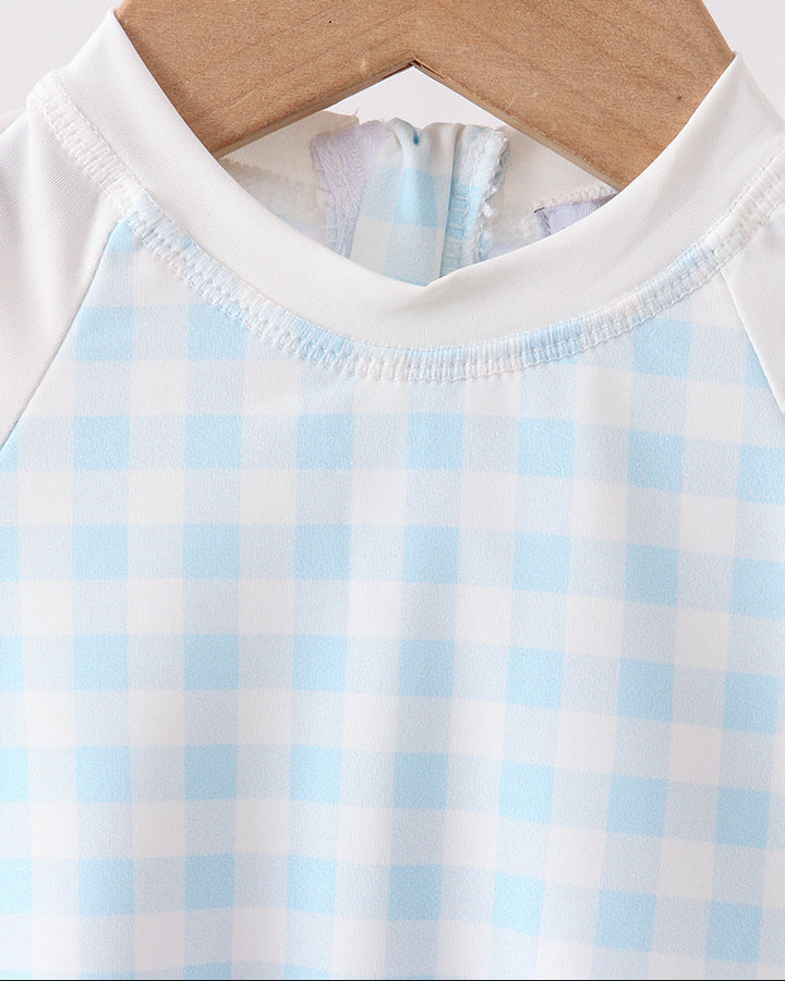 Swimsuit with blue and white checkered pattern on a wooden hanger