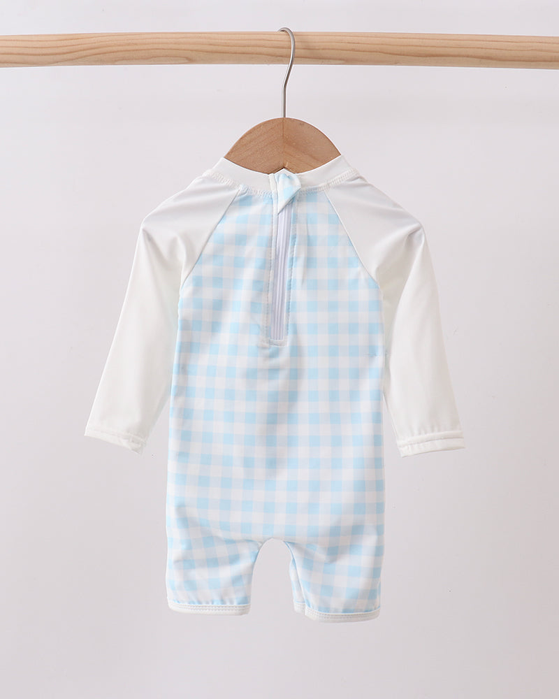 Baby swimsuit with blue checkered pattern on a hanger against a white background