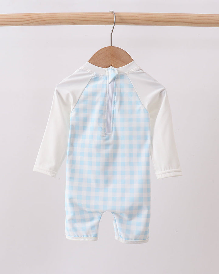 Baby swimsuit with blue checkered pattern on a hanger against a white background