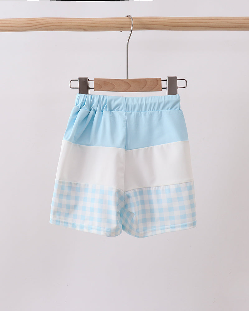 Pair of shorts with a blue and white checkered pattern hanging on a wooden rack.